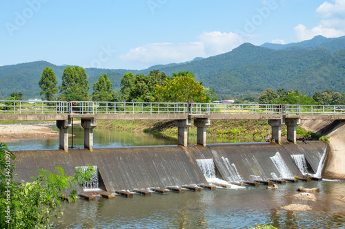 Concrete bridge over the weir in the river. Which flows from the mountains