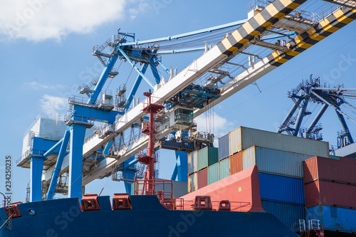 Container ship in port at container terminal close-up. Ships of container ships stand in terminal of port on loading, unloading container.