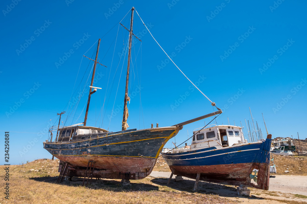 Two small aged boats stays on the ground at Paros, Greece