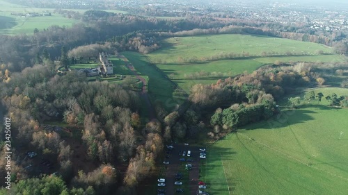 Aerial footage flying away from the Hunting lodge at Chatelherault country park over woodland and a car park. photo