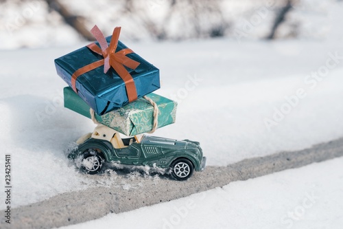 Outdoor toy vintage retro car with gifts for Christmas and New Year, car on a snowy road. Sunny frosty winter day, a lot of snow