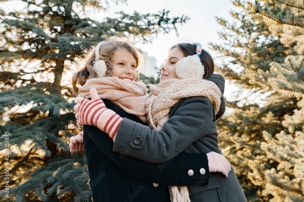 Outdoor winter portrait of two little girls smiling and having fun near the Christmas tree, golden hour Outdoor winter portrait of two little girls smiling and having fun near the Christmas tree, golden hour