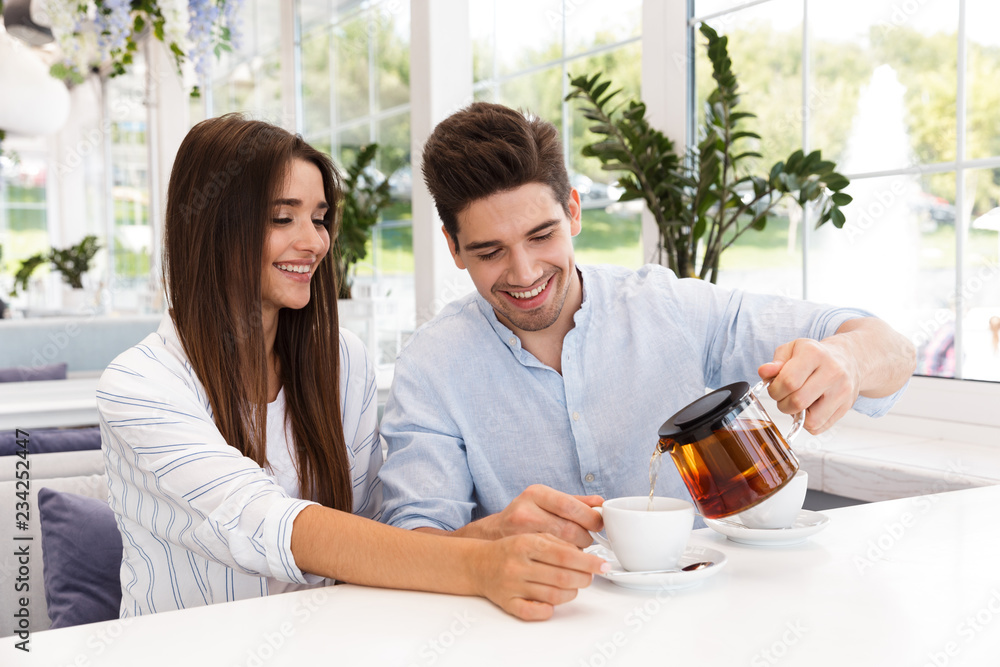 Happy young couple sitting at the cafe table Happy young couple sitting at the cafe table