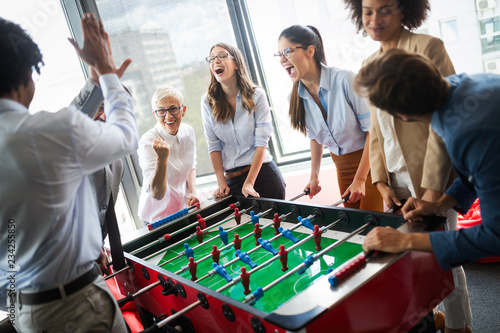 Fotografie Employees playing table soccer indoor game in the office during break time