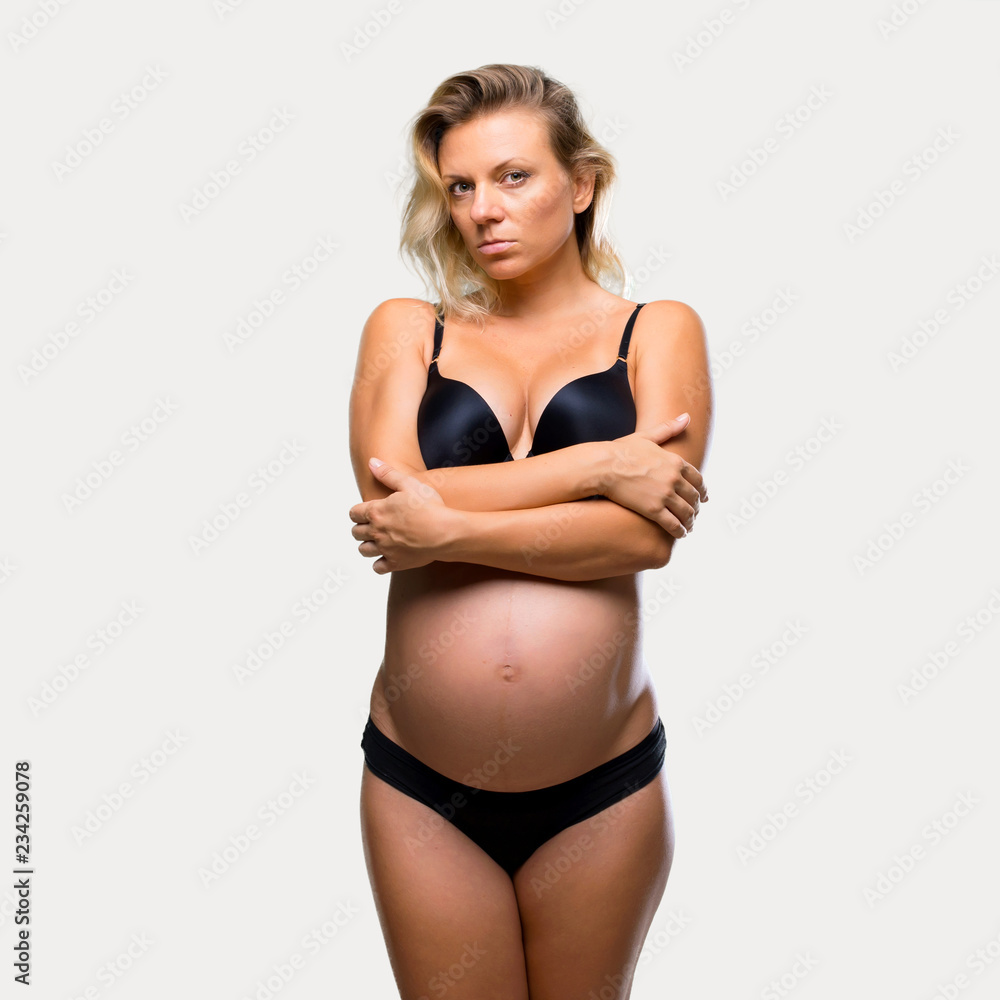 Blonde pregnant woman in underwear on isolated grey background Blonde pregnant woman in underwear on isolated grey background
