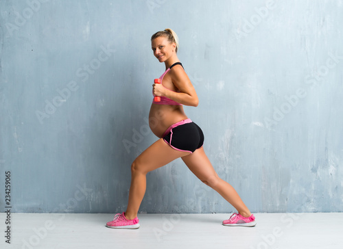 Blonde pregnant woman doing sport making weightlifting