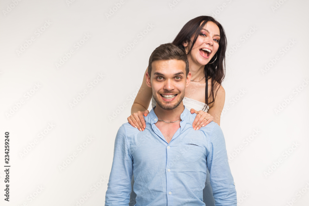 Happy young girlfriend jumps on the back of her boyfriend on white background Happy young girlfriend jumps on the back of her boyfriend on white background