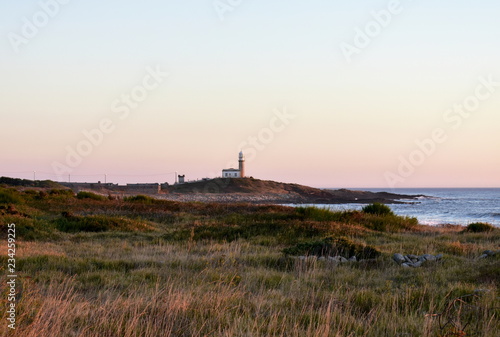 Old abandoned lighthouse with sunset light. Galicia, Spain, sunny day, red and blue sky.