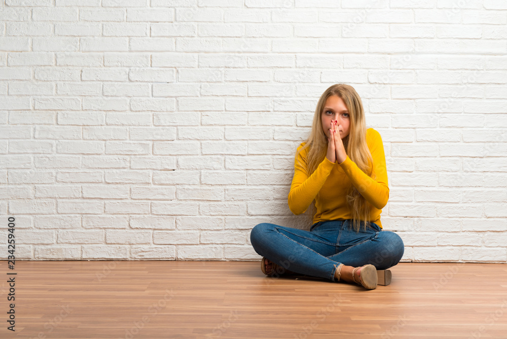 Young girl sitting on the floor keeps palm together. Person asks for something Young girl sitting on the floor keeps palm together. Person asks for something