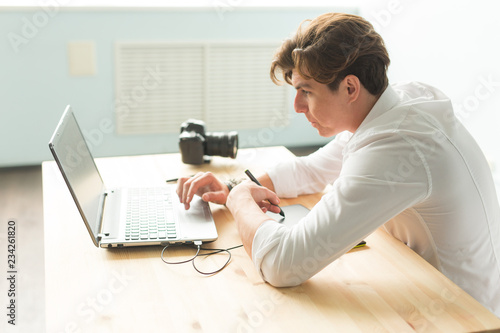 Business, technology, people concept - handsome man working with graphic tablet. He is an architector or multiplicator or designer photo