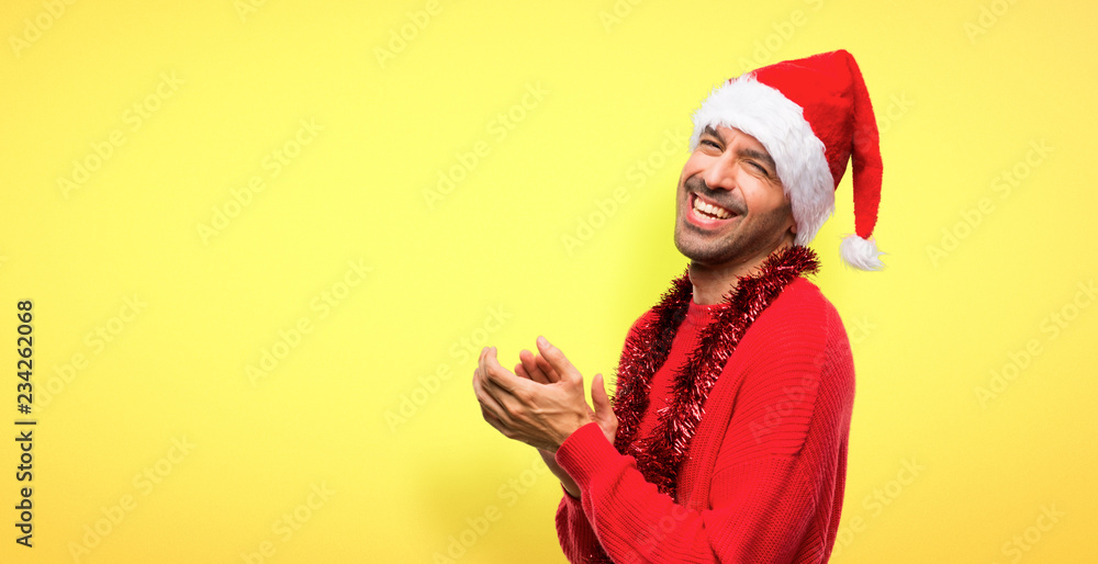 Man with red clothes celebrating the Christmas holidays applauding after presentation in a conference on yellow background Man with red clothes celebrating the Christmas holidays applauding after presentation in a conference on yellow background