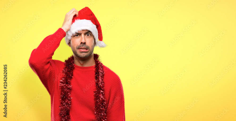 Man with red clothes celebrating the Christmas holidays with an expression of frustration and not understanding on yellow background Man with red clothes celebrating the Christmas holidays with an expression of frustration and not understanding on yellow background