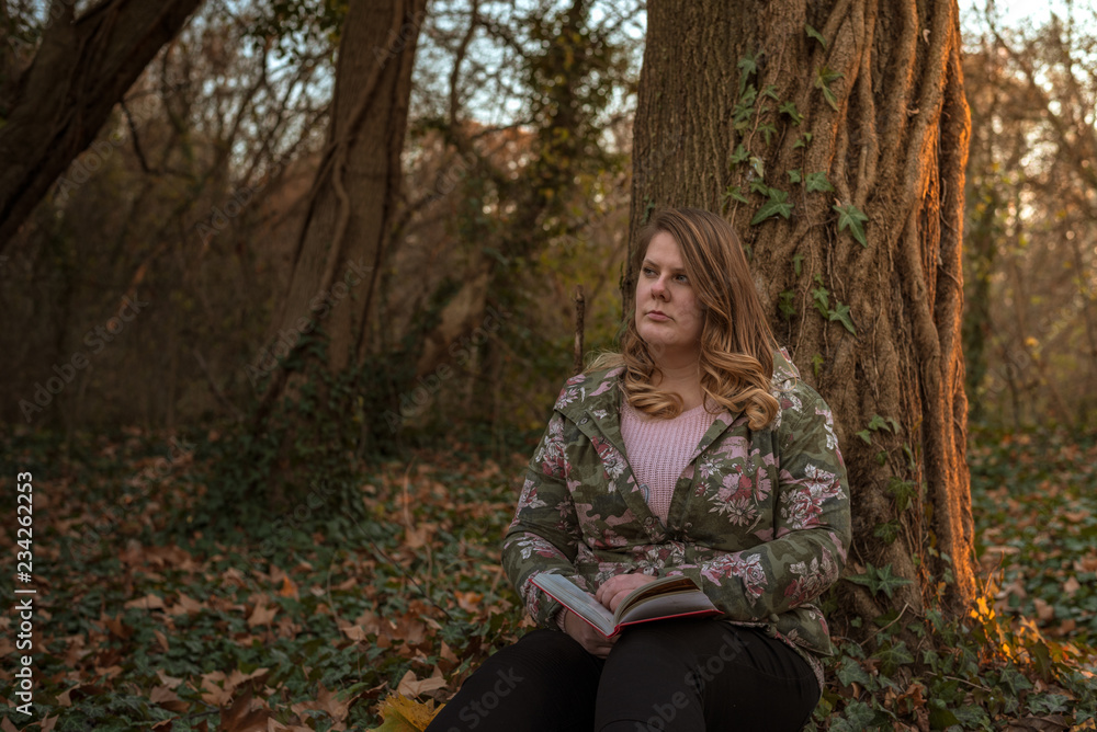 A beautiful plus size woman is reading in the autumn park A beautiful plus size woman is reading in the autumn park