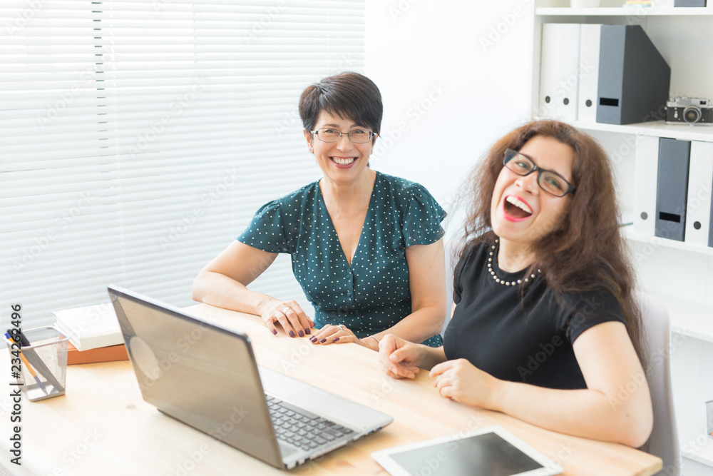 Two happy business women working together in office interior Two happy business women working together in office interior
