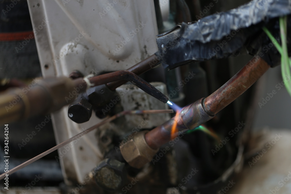 Technician are soldering a coil with copper in order to fix leakage of