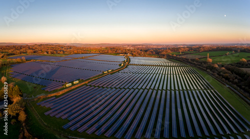 Aerial drone view of solar panels at a solar energy generation farm at Sunset in South Wales, UK