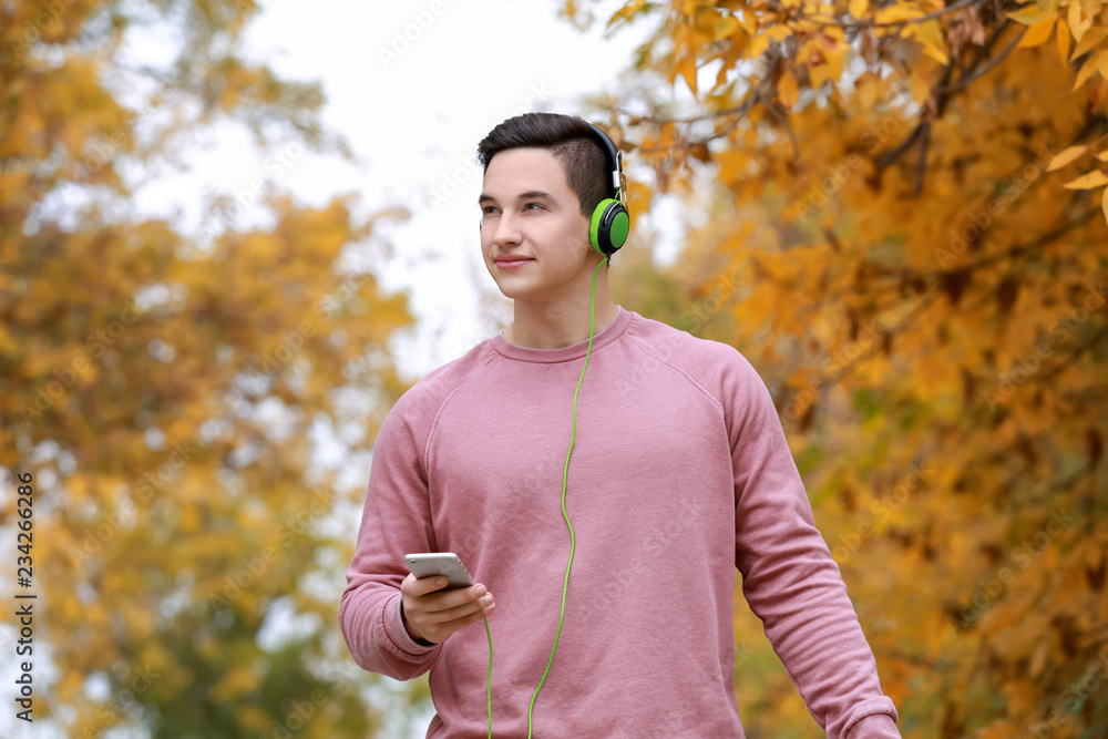 Obraz premium Young man listening to music in autumn park