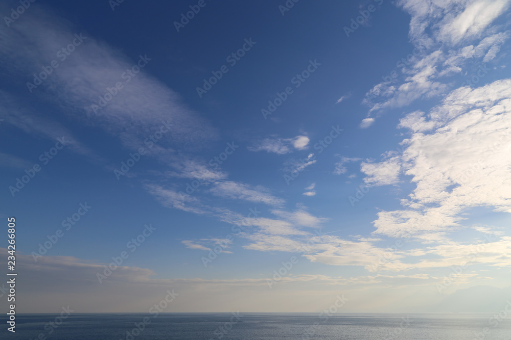 Peaceful sky over Mediterranean sea on sunny summer afternoon. Light clouds over ocean background. Tranquility and serenity.