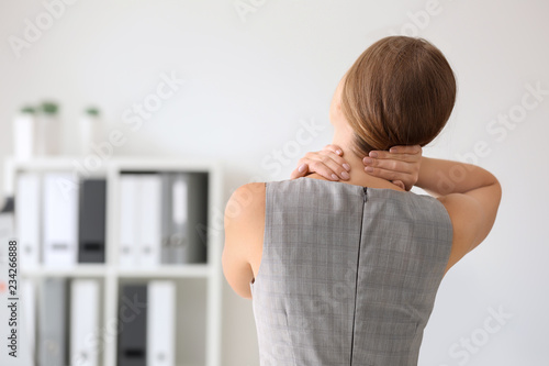 Young woman suffering from neck pain in office photo