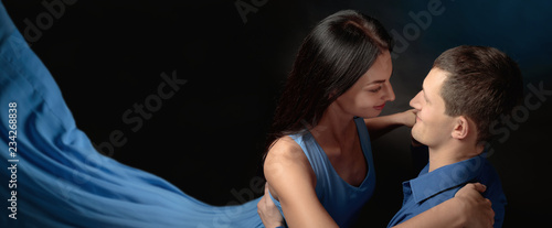 Young beautiful woman in long blue dress and man in blue shirt dancing tango.