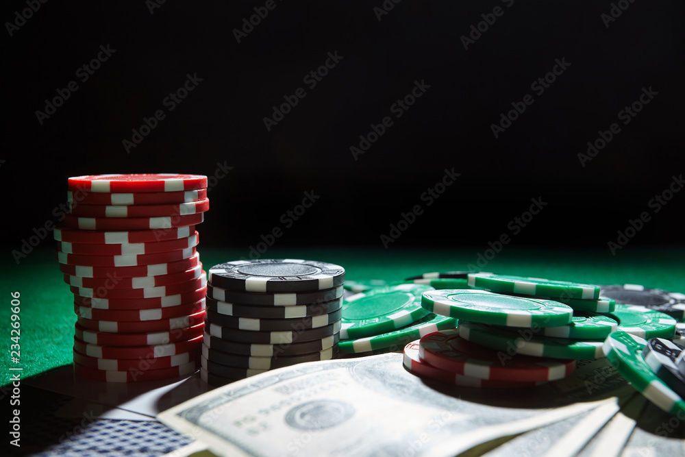 A stack of gambling chips, cards one hundred dollar bills on green table. A stack of gambling chips, cards one hundred dollar bills on green table.