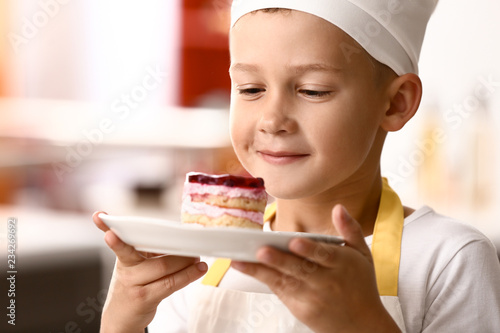 Cute little chef with tasty dessert in kitchen