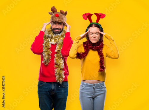 Couple dressed up for the christmas holidays unhappy with something. Negative facial expression on yellow background