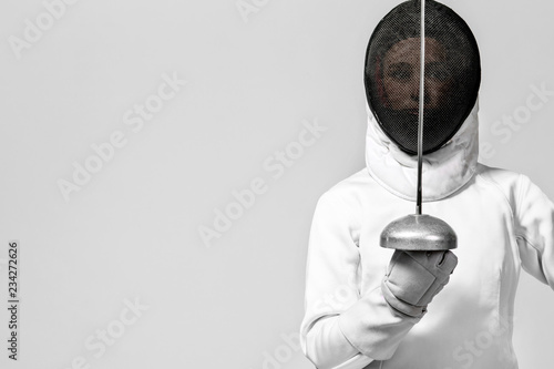 Fotografija Young fencer athlete wearing fencing costume holding the sword and mask
