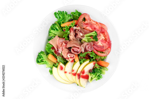Salad with prosciutto, pear, tomato, carrot and broccoli in a white plate isolated on white background. top view. flat lay