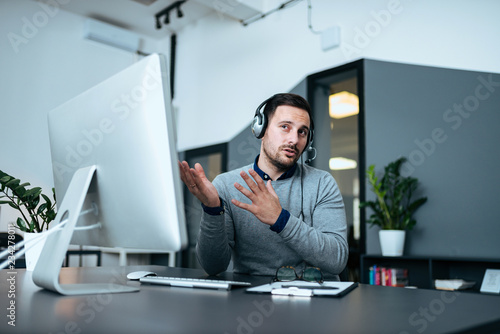 Billede på lærred Puzzled handsome technical support agent trying to explain something to a client