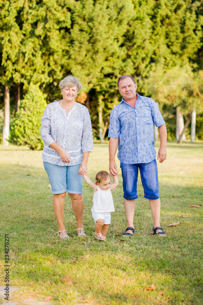 Fototapeta premium Young grandmother and grandfather on a walk with their granddaughter
