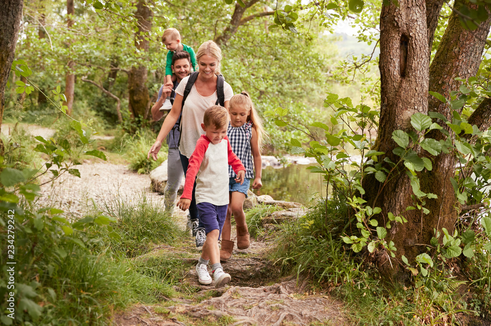 Fototapeta premium Family Hiking Along Path By River In UK Lake District