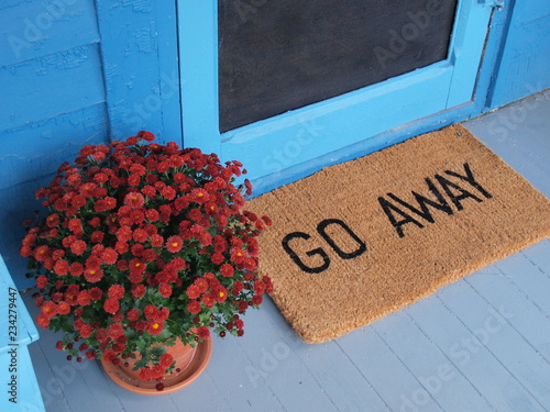 Unwelcoming welcome mat says Go Away on a pretty porch