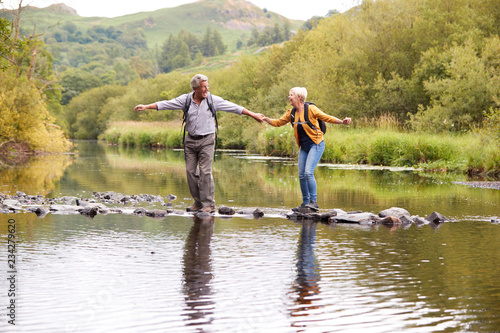 фотографія Senior Couple Crossing River Whilst Hiking In UK Lake District