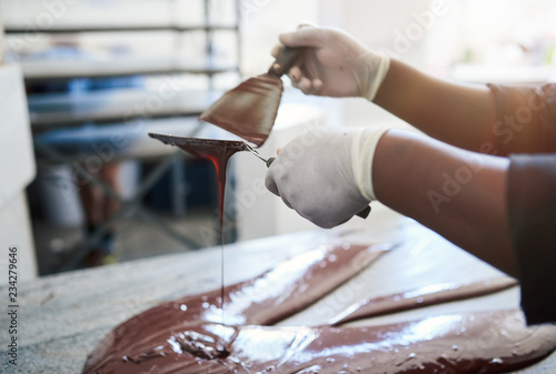 Worker mixing artisanal chocolate with spatulas on a table © mavoimages