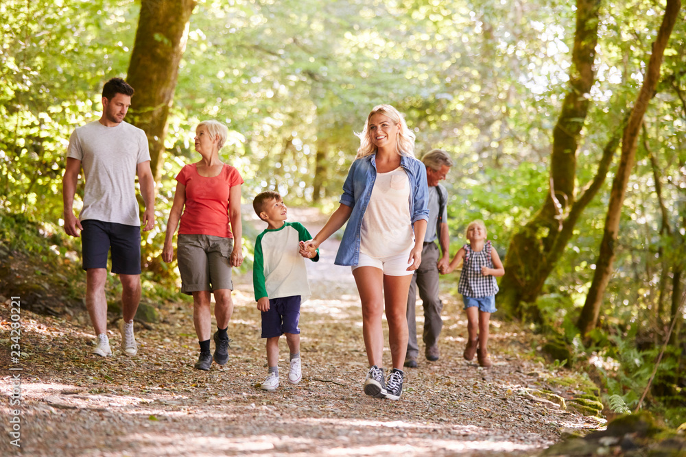 Multi Generation Family Enjoying Walk Along Woodland Path Together Multi Generation Family Enjoying Walk Along Woodland Path Together