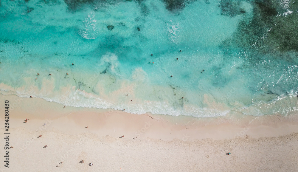 Incredible view of the white sandy beach from a bird's eye view. Top view of beautiful white sand beach with turquoise sea water and palm trees, aerial drone shot. 
