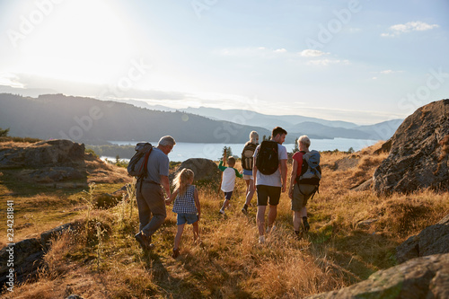 фотографія Rear View Of Multi Generation Family Walking On Top Of Hill On Hike Through Coun