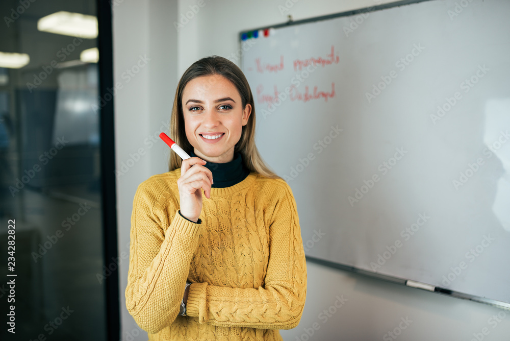 Φωτογραφία Portrait of a young casual female entrepreneur holding marker, standing in front of whiteboard