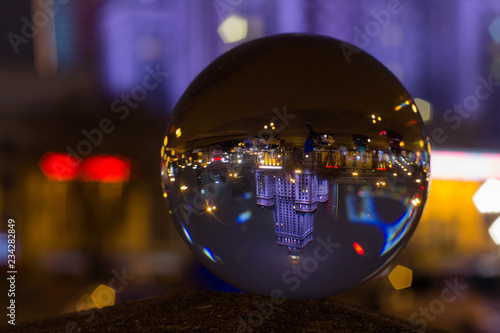Palace of Culture and Science Warsaw - captured flipped reflection in crystal ball at night in rainy autumn time.