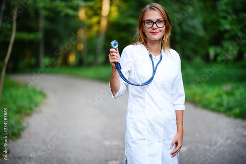 a young girl who is a doctor stands outside, holds the stethosco photo