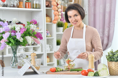 Portrait of beautiful smiling woman cooking at kitchen