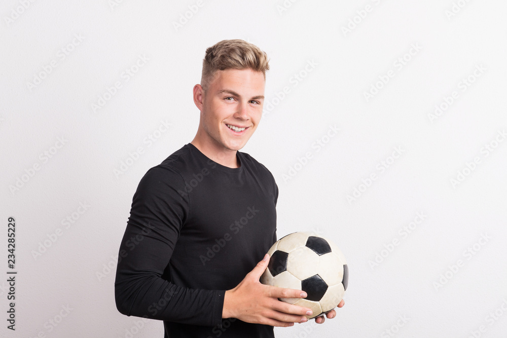 Portrait of a young man with football ball in a studio. Copy space. Portrait of a young man with football ball in a studio. Copy space.