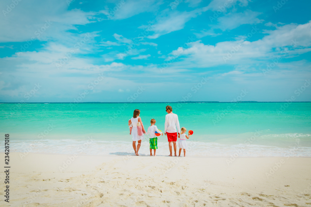 happy family with three kids walk on beach