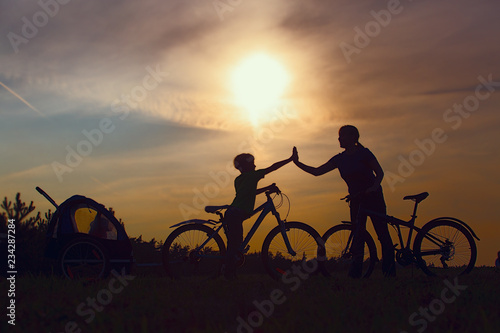 happy family -mother with kids riding bike at sunset
