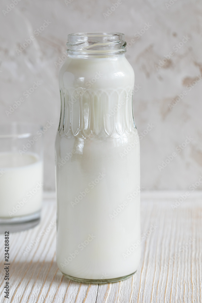 Close-up bottle with kefir is standing on white wooden table on white background. Close-up bottle with kefir is standing on white wooden table on white background.