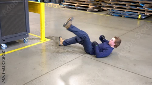 A young male worker slipping on a wet floor in a factory.  An industrial safety topic. photo