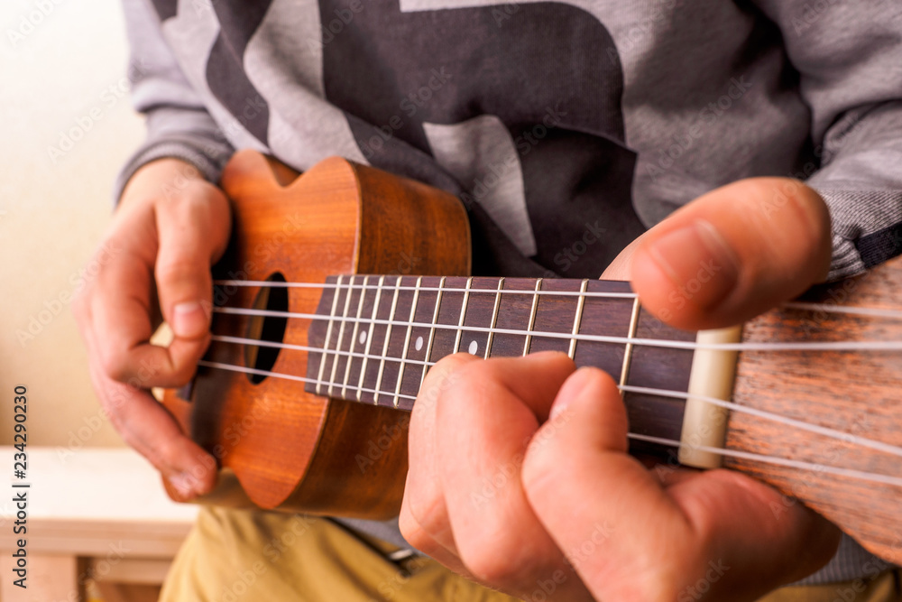A man playing guitar ukulele in close up view.