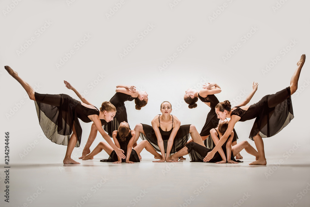 Obraz premium The group of modern ballet dancers dancing on gray studio background