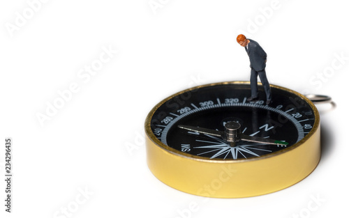 miniature figure businessman in dark blue suit standing on golden compass for finding the way how to success of business and financial
